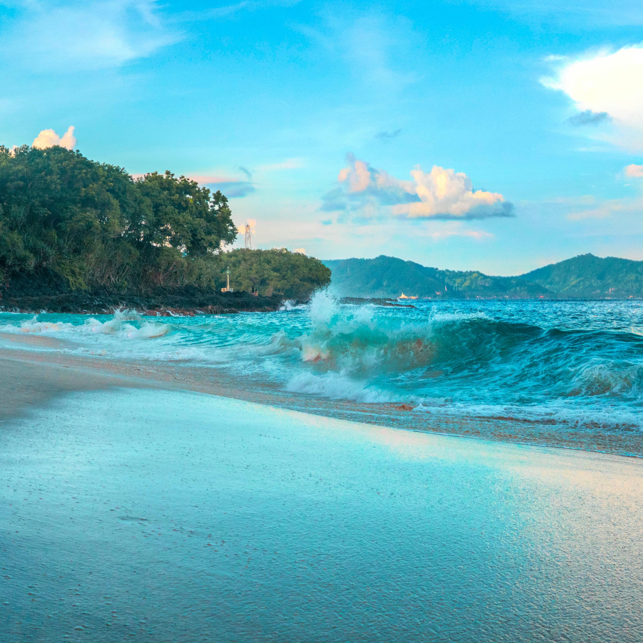 Serene sandy beach with vibrant turquoise waters and lush greenery in Bali, Indonesia.